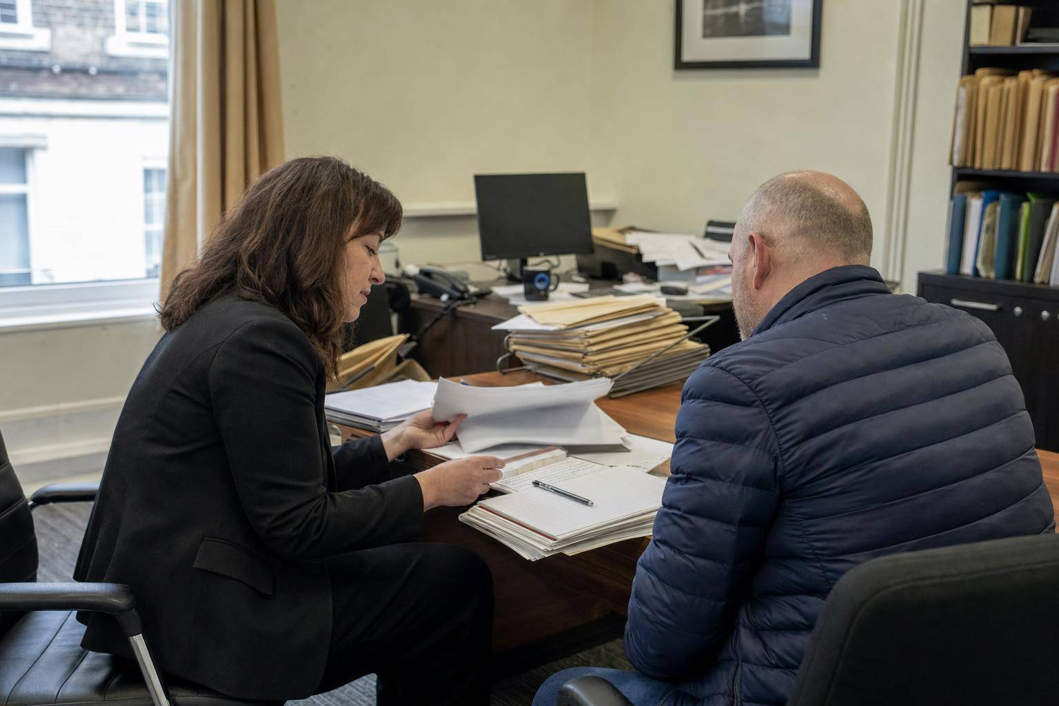 A client and legal adviser reviewing organised documents during a consultation